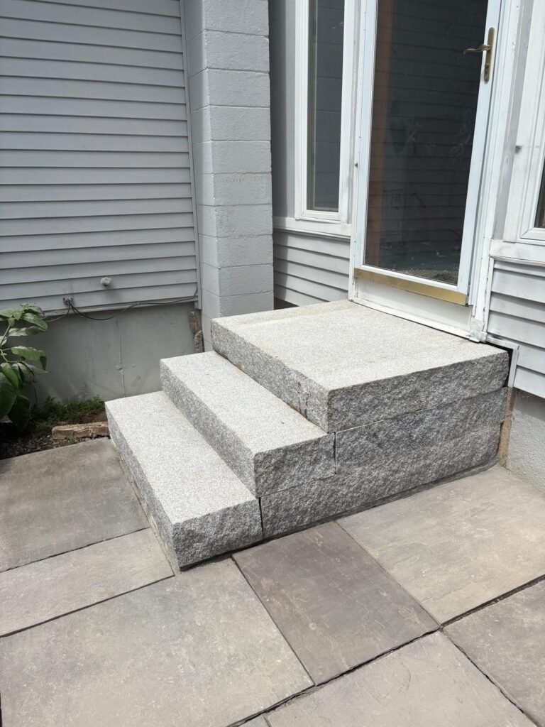 New solid granite steps installed at a back door over a bluestone patio