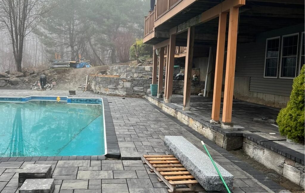 Paver pool patio renovation with stone coping and a stone retaining wall